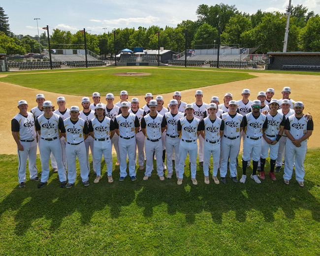 Elevated drone shot of the 2023 Redding Colt 45s team standing three rows deep, in the shallow outfield, behind second base, with home plate and the stands in the background. [Formatted]